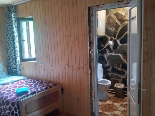 um quarto com uma cama e uma casa de banho com uma parede de pedra em Stone House marexi em Adishi