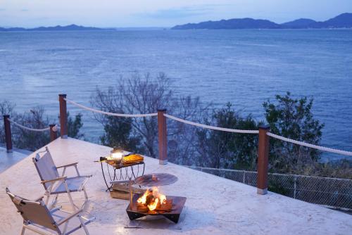 eine Terrasse mit Stühlen, einem Tisch und einer Feuerstelle in der Unterkunft SETO CLAS AJI THE SEASIDE HILLS RESORT in Aji