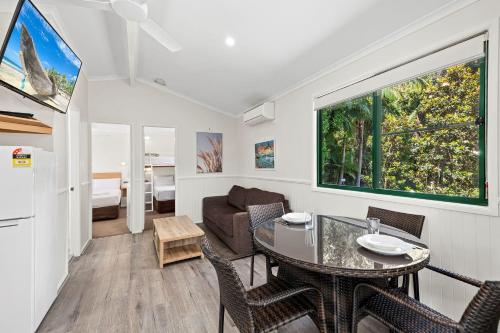 a living room with a table and chairs and a couch at Sapphire Beach Holiday Park in Coffs Harbour