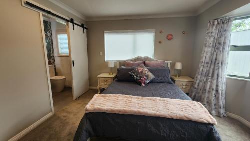 ein Schlafzimmer mit einem großen Bett und einem Fenster in der Unterkunft Petit Paradis in Whitianga
