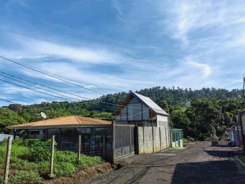 um edifício com uma cerca ao lado de uma montanha em Casa Rústica Pura Vibra em Alajuela