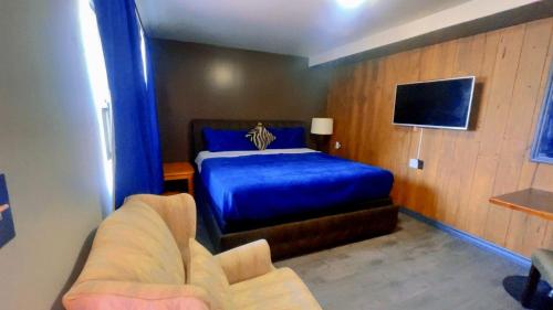 a bedroom with a blue bed and a couch at Crestwood Motel in Burlington