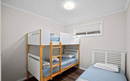 Habitación pequeña con 2 literas y ventana en Sapphire Beach Holiday Park en Coffs Harbour