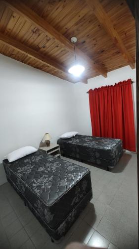 2 camas en una habitación con cortinas rojas en DON ALBERDI ALOJAMIENTOS en San Rafael
