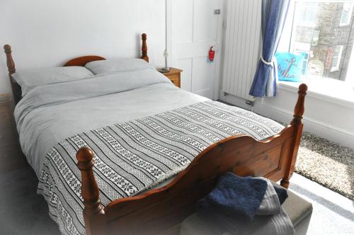 a bedroom with a bed with a wooden frame and a window at Gordon House B & B in Tintagel