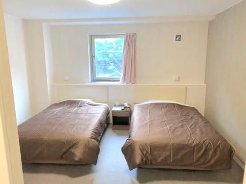 sypialnia z 2 łóżkami i oknem w obiekcie 阪南国际HOTEL w mieście Hannan