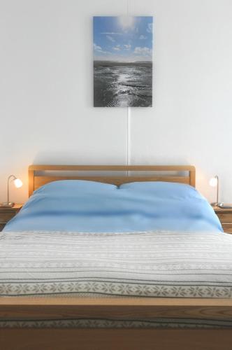 a bedroom with a bed with a painting on the wall at Gordon House B & B in Tintagel