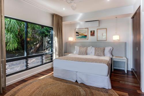 a bedroom with a bed and a large window at Point Blue on Hamilton Island by HIHA in Hamilton Island