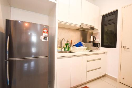 a kitchen with a stainless steel refrigerator and white cabinets at Meridin Medini Suite by Nest Home【LEGOLAND】 in Nusajaya