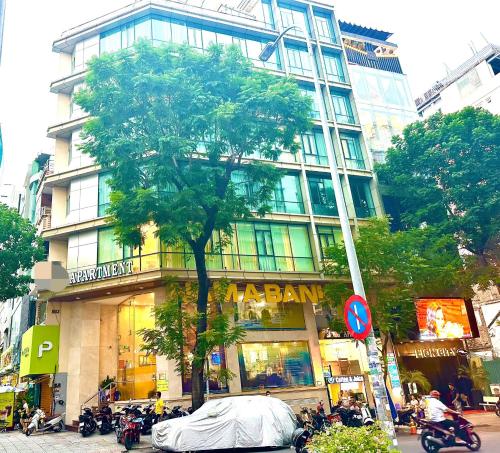 a large building with a tree in front of it at SANG Hotel Apartment Sai Gon in Ho Chi Minh City