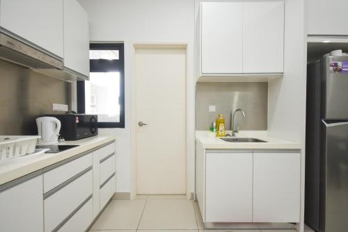 a white kitchen with white cabinets and a sink at Meridin Medini Suite by Nest Home【LEGOLAND】 in Nusajaya