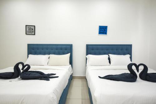 two swans sitting on two beds in a room at Meridin Medini Suite by Nest Home【LEGOLAND】 in Nusajaya
