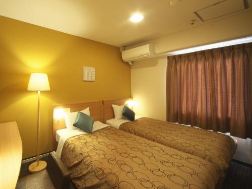 ein Hotelzimmer mit 2 Betten und einer Lampe in der Unterkunft Yokohama Heiwa Plaza Hotel in Yokohama