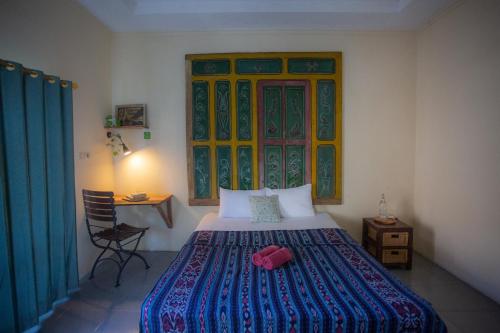 a bedroom with a bed and a desk and a window at Rumah Kalpataru in Yogyakarta