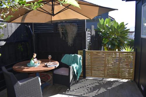 a patio with a table and an umbrella at Private Beachside Studio with Courtyard and Sea view in Paraparaumu