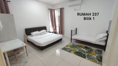 a bedroom with two beds and a table and a window at Homestay Kolam Renang Sungai Petani in Sungai Petani