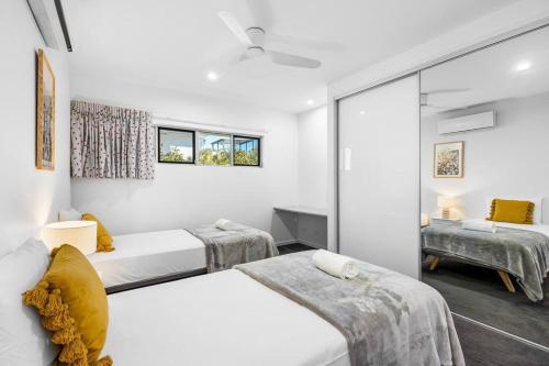 a bedroom with two beds and a mirror at Ocean Blue @ Alex in Alexandra Headland
