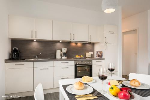 une cuisine avec des armoires blanches et une table avec des assiettes de nourriture dans l'établissement Heimathafen 2 - M S Küselwind, à Kappeln