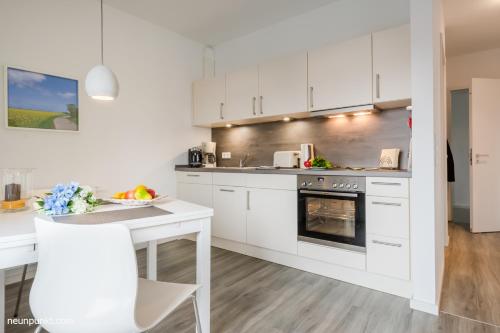 une cuisine avec des armoires blanches, une table et un four dans l'établissement Heimathafen 3 - M S Atlantis, à Kappeln