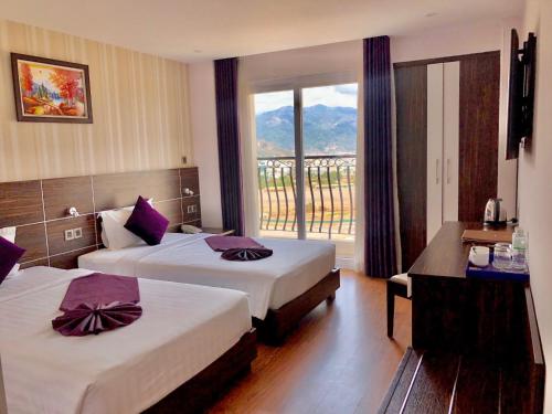 a hotel room with two beds and a balcony at Balcony Nha Trang Hotel in Nha Trang