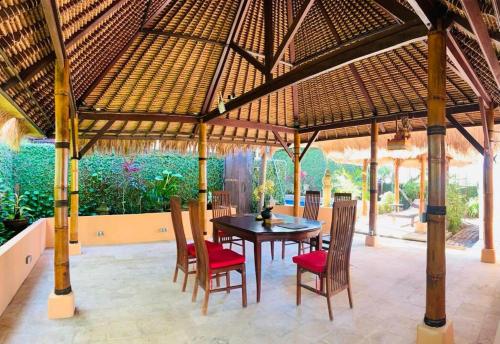 a dining room with a table and chairs under a pavilion at Giri's Villa Jimbaran in Ungasan