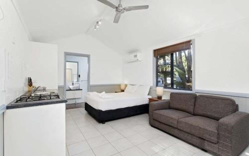 een woonkamer met een bank en een bed bij Sapphire Beach Holiday Park in Coffs Harbour