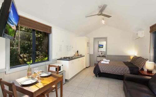 a living room with a bed and a dining room at Sapphire Beach Holiday Park in Coffs Harbour