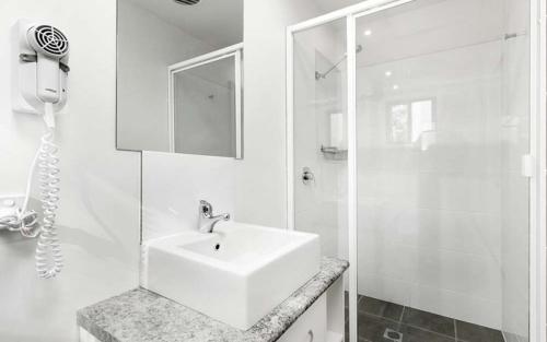 a white bathroom with a sink and a shower at Sapphire Beach Holiday Park in Coffs Harbour