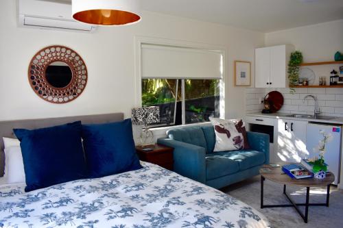 1 dormitorio con 1 cama azul y 1 sofá azul en Paraparaumu Beachside Studio en Paraparaumu