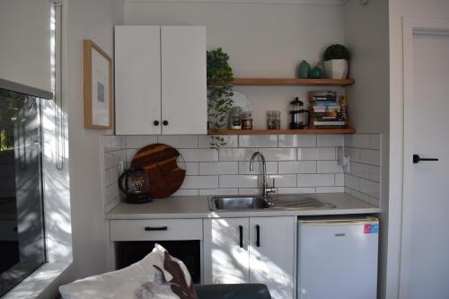 una cocina con armarios blancos y fregadero en Paraparaumu Beachside Studio en Paraparaumu