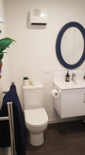 a white bathroom with a toilet and a sink at Private Beachside Studio with Courtyard and Sea view in Paraparaumu