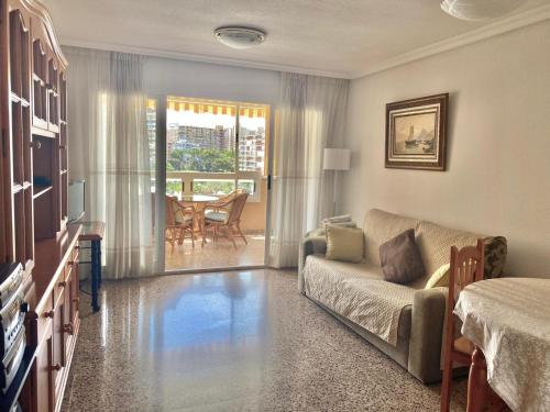 ein Wohnzimmer mit einem Sofa und einem Tisch in der Unterkunft Apartamento Atenas Piscina 4 pax, Inmobiliaria Leo Playa de San Juan in Alicante