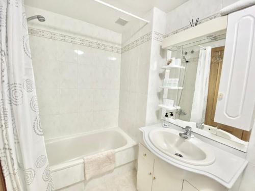 een witte badkamer met een wastafel en een bad bij Apartamento Atenas Piscina 4 pax, Inmobiliaria Leo Playa de San Juan in Alicante
