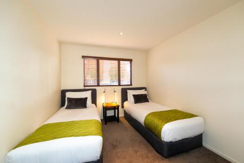 two beds in a small room with a window at Harvest Lodge Motel in Havelock North