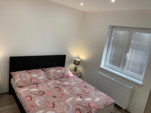 1 dormitorio con 1 cama con colcha rosa y 2 ventanas en Apartmán Růže, en Mařenice