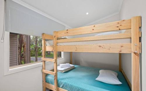 a bunk bed in a small room with a window at Sapphire Beach Holiday Park in Coffs Harbour