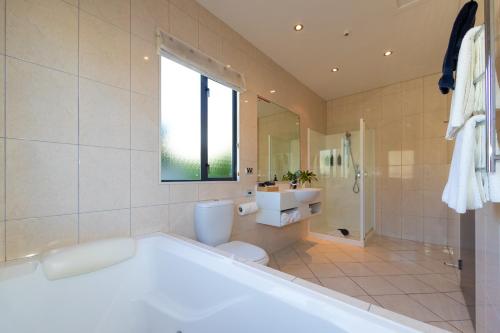 a bathroom with a tub and a toilet and a sink at Harvest Lodge Motel in Havelock North