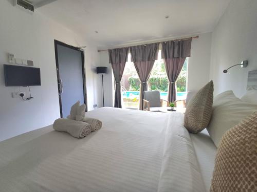 a bedroom with a large white bed with a stuffed animal on it at Tisha Langkawi Wellness Resort in Pantai Cenang