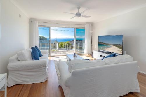 a living room with two white couches and a tv at Ocean View in Forster
