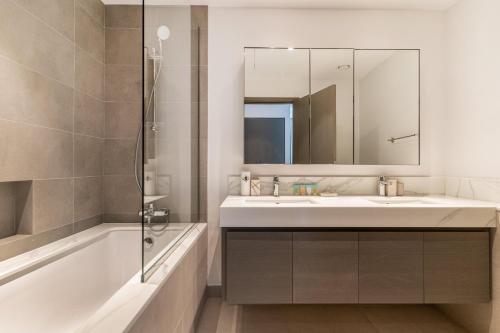a bathroom with a sink and a tub and a mirror at Creek Horizon - 2BR Apartment - Allsopp&Allsopp in Dubai