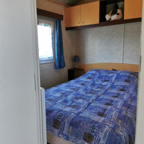 1 dormitorio con 1 cama con edredón azul en Parc étang de besse, en Saint-Hilaire-de-Riez