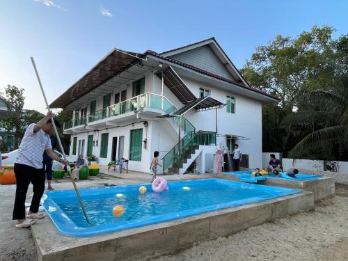 a woman playing baseball in a pool in front of a house at Akram Homestay in Kota Bharu