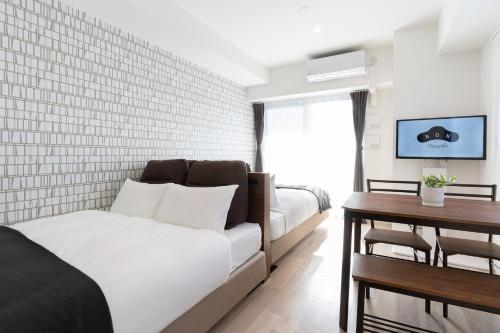 a hotel room with two beds and a table at Hotel Abitare Namba West in Osaka