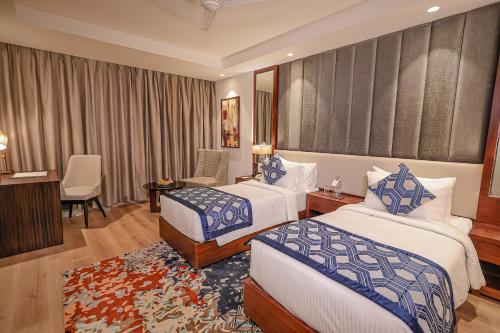 a hotel room with two beds and a desk at Regenta Dehradun by Royal Orchid Hotels Limited in Dehradun