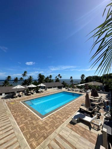a large swimming pool with chairs and umbrellas at The Crow's Nest Resort Fiji in Korotogo
