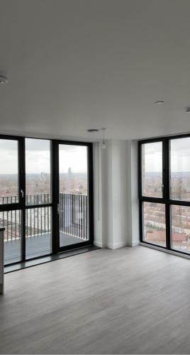 Habitación vacía con ventanas grandes en un edificio en Spacious & Cozy One Bedroom Flat, en Dagenham