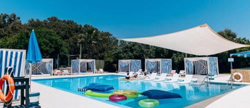 una gran piscina con sillas y sombrilla en NEA Resort & People, en Shave Ẕiyyon