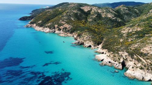 an aerial view of an island with blue water at holiday house "Lo Stuggio" Pinus Village chia in Fort Village