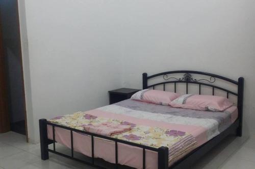 a bed with a black frame and pink pillows on it at Cozy Homestay in Central Pokok Sena in Pokok Sena