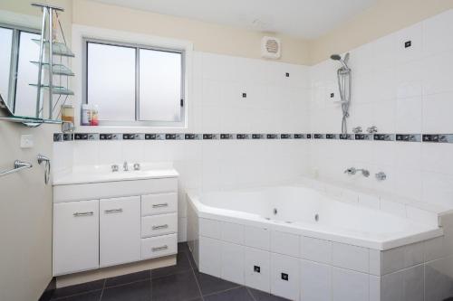 Baño blanco con bañera y lavamanos en San Remo Views, en San Remo